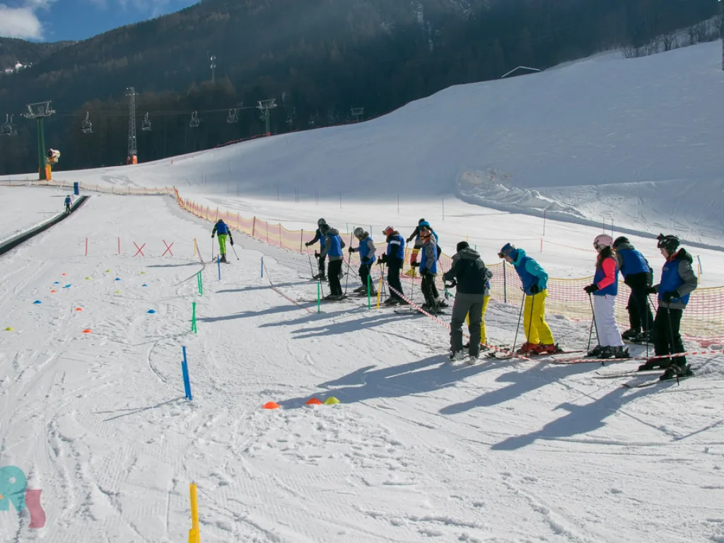 Skigruppe übt zwischen Markierungsstangen auf der Piste.